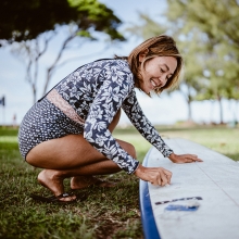 Woman waxing surfboard in Honolulu