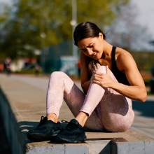 Woman in pain holding knee while on morning run