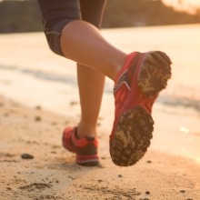 Woman training for Honolulu Marathon running on the beach at sunset.
