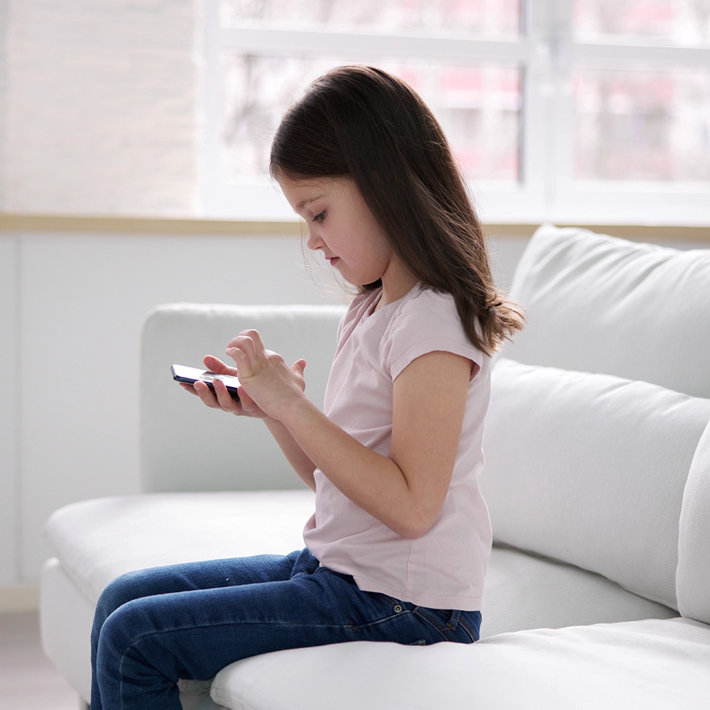 Child reading phone on couch